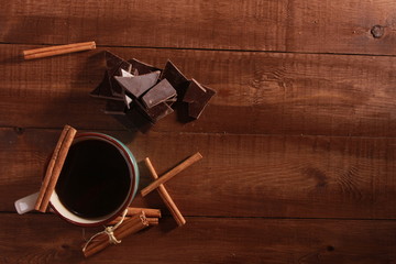 Coffee, cinnamon sticks, pieces of chocolate and scattered beans on vintage wooden table. Coffee break concept. Blue cup, winter drink, espresso, top view