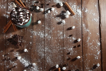 Cocoa, marshmallow, cinnamon sticks, pieces of chocolate and sugar powder on vintage wooden table. Desserts, sweets or coffee shop concept. Blue cup, winter drink, top view, confection