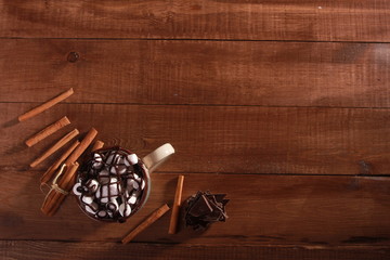 Cocoa, marshmallow, cinnamon sticks and pieces of chocolate on vintage wooden table. Coffee shop or desserts concept. Blue cup, winter drink, top view, confection