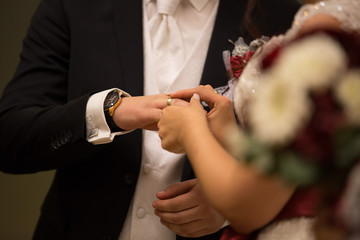 Obraz na płótnie Canvas bride putting ring on grooms hand