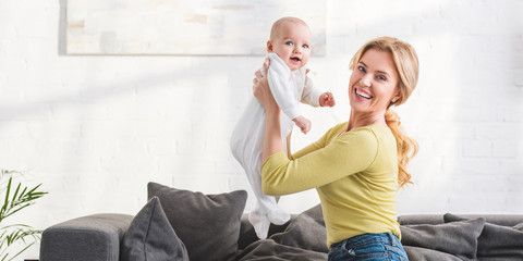 happy mother holding beautiful infant child and smiling at camera