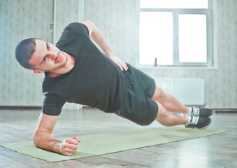 Healthy Sporty Man Doing Indoor Side Plank Exercise on Mat, Static Exercise.