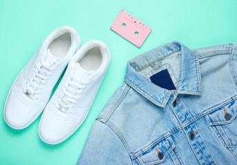 Retro style denim stylish jacket, audio cassette and white hipster sneakers on a mint-colored paper...