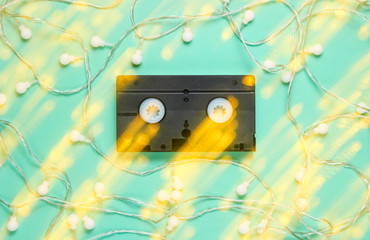 Retro vhs video tape with bright glowing led garlands on blue background. Light effect Top view, minimalism. .