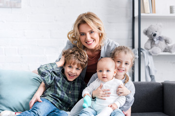 beautiful happy mother with three adorable children smiling at camera