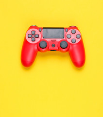 Modern red gamepad (joystick) on a yellow background. Top view.