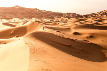 Fototapeta na wymiar Lonely Berber walking in Erg Chebbi desert