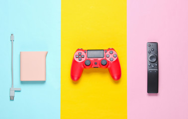 Power bank, red gamepad, tv remote on a colored paper background. Top view. Modern gadgets and accessories for recreation.. © splitov27