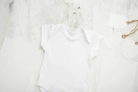 Layout Flat Lay a white children's body shirt, on a white background, for a girl with white postcards and tags. Choose design and placement of logos, advertising