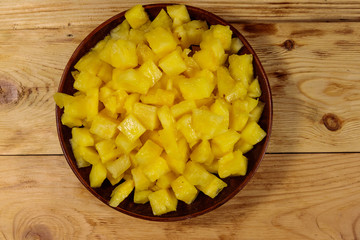 Diced pineapple in a plate on wooden table. Top view