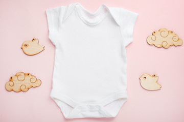 Layout Flat Lay white baby bodysuit shirt, on a pink background, for a girl with wooden toys. Mock up for design and placement of logos, advertisements