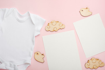 Layout Flat Lay white baby bodysuit shirt, on a pink background, for a girl with wooden toys and white empty cards and tags.Mock up for design and placement of logos, advertisements