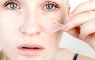The girl removes the mask film from the face. The concept of removing old dry skin, self-care