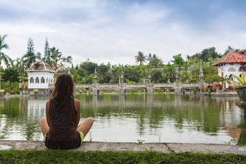 Girl sitting on pier and lookingat the river in Bali