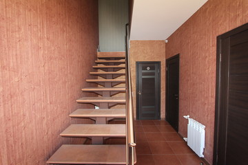 Open staircase with stone steps going up to the inside corridor rooms close-up on a background of bright walls and dark doors