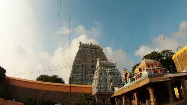 Gates tower of southern Indian temple complex roof with colorful statues blue sky with white clouds sun shines