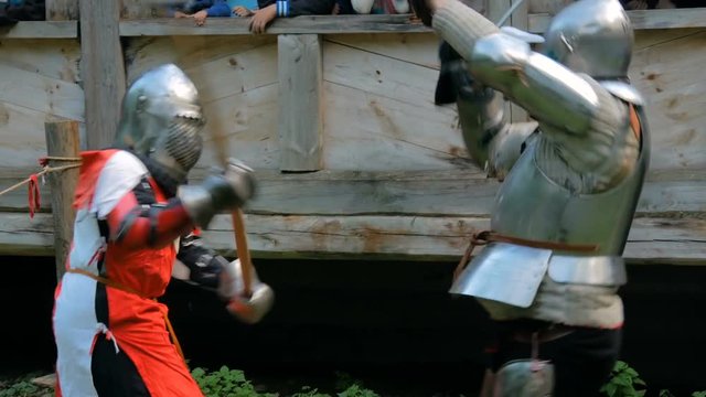 Two militant medieval knights fighting at historical festival. Fantasy, history, reenactment and medieval culture concept