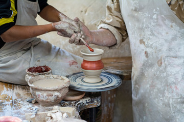 A potter teaches a child how to make a pot of clay.