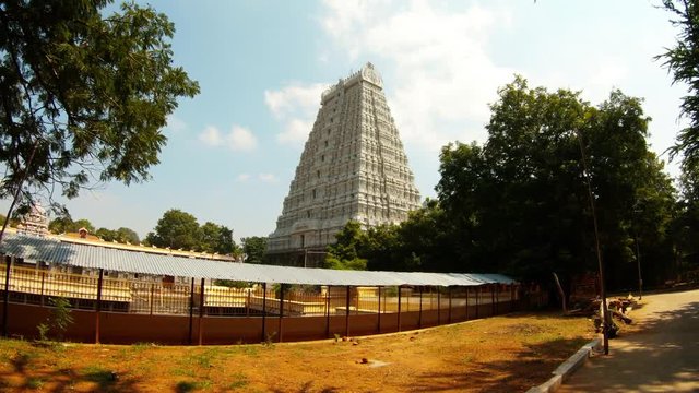 Majestic sculptural gate tower southern Indian style of architecture Tiruvannamalai temple complex blue sky green trees