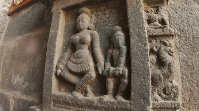 Ancient stone carving preserved in southern Indian temple image of Female giant with naked breast and small man with drum