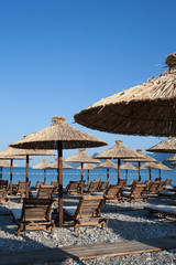 Bamboo umbrellas and wooden deck chairs on the sandy beach by the sea