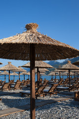 Bamboo umbrellas and wooden deck chairs on the sandy beach by the sea