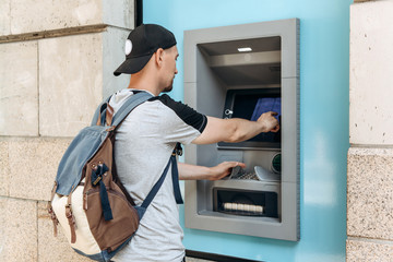 The tourist withdraws money from the ATM for further travel. Finance, credit card, withdrawal of money. Life style. Journey. Vacation. Grabs a card from the ATM.