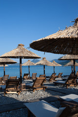 Bamboo umbrellas and wooden deck chairs on the sandy beach by the sea
