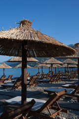 Bamboo umbrellas and wooden deck chairs on the sandy beach by the sea