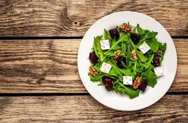 Salad of arugula, cheese, beet, walnut, on a wooden table