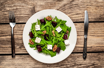 Salad of arugula, cheese, beet, walnut, on a wooden table