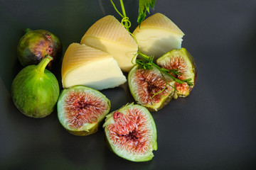 Pieces of cheese and figs on a brown surface. Sun rays on sliced figs. Summer Provence.