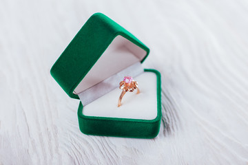 Golden ring with amethyst in green gift box on white background. Present for Valentines day