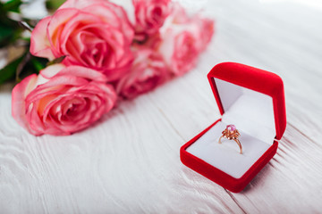 Golden ring with amethyst in red gift box and bouquet of roses. Present for Valentines day