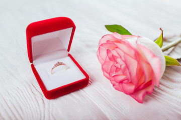 Golden ring with diamonds in red gift box and bouquet of roses. Present for Valentines day