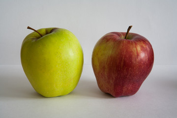 Useful fruits - one red and one green apple on white background