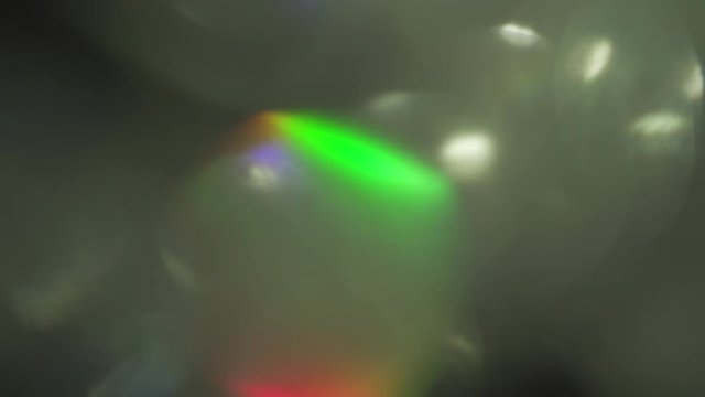 Iridescent holographic light leaks on dark background, 4k resolution.