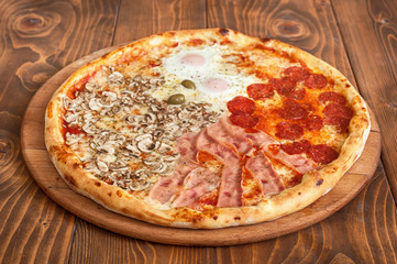 Fresh italian four seasons pizza on wooden background, side view