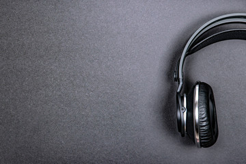 Black professional headphones on a dark silver background.