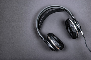 Black professional headphones on a dark silver background.