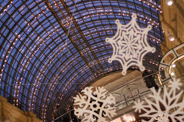 The blue glass dome of a building with a multitude of burning lamps and hanging snowflakes