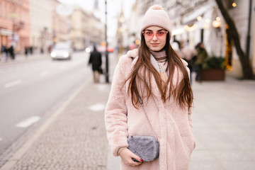 Fashion woman walking on the city street, wear pantone color jaket with pink glasses and look to camera. Copy space. - Image