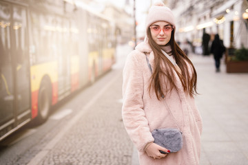 Fashion woman walking on the city street, wear pantone color jaket with pink glasses and look to camera. Copy space. - Image