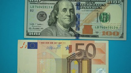 dollars and euro banknotes on blue background. moving from different sides, meet at middle for a second and then moving out. looped closeup 4k video. Europe United States business trade concept - Powered by Adobe