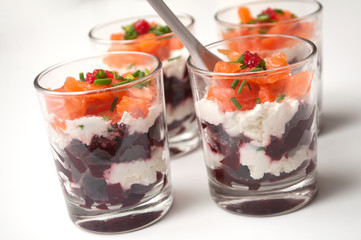closeup of beet and salmon appetizers in little glasses on white background
