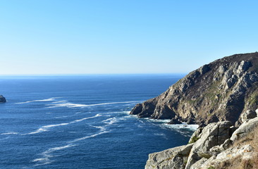 Cliff at Finisterre, &ldquo;The End of the World&rdquo;. Rocks and blue sea with foam. Sunny day, Galicia, Spain.