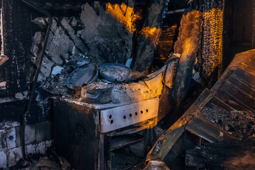 Burnt house interior. Burned kitchen, remains of stove and furniture in black soot