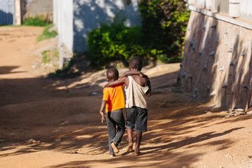 boys walking arm in arm in Uganda, Africa - obrazy, fototapety, plakaty