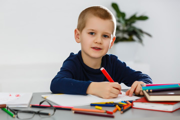 Education, childhood, people, homework and school concept - smiling student boy with book writing to notebook at home