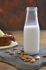 Homemade Almond milk in bottle with almonds in a bowl. Dairy alternative milk - close up with space for text